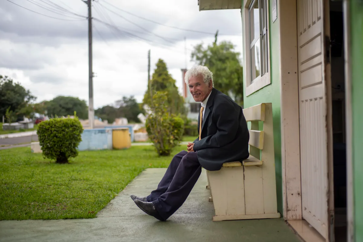Morador sentado diante de uma casa do Pequeno Cotolengo